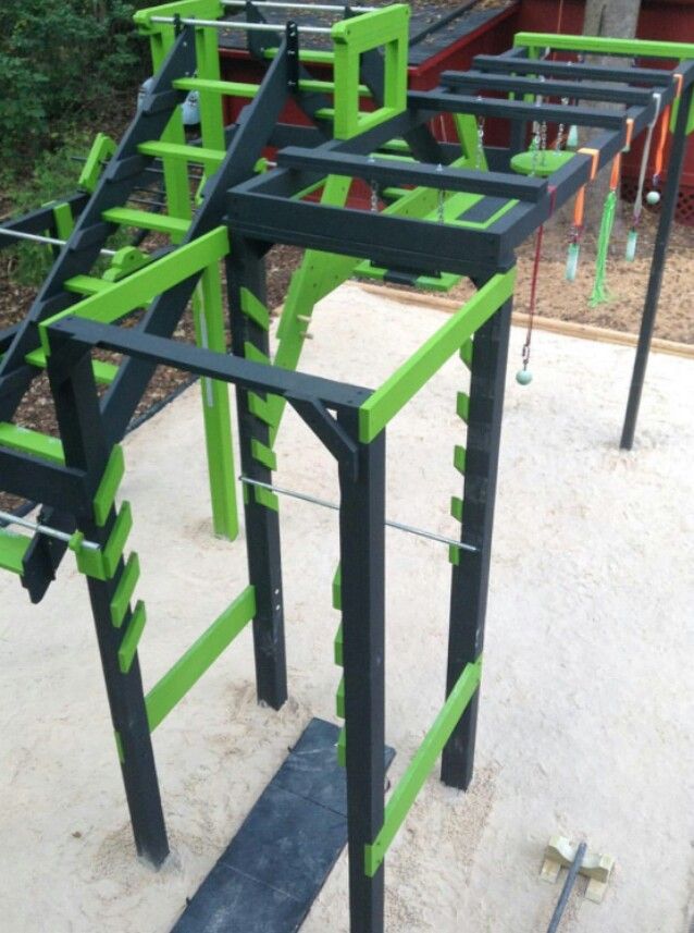 a group of green and black metal structures in the middle of a yard with trees behind it