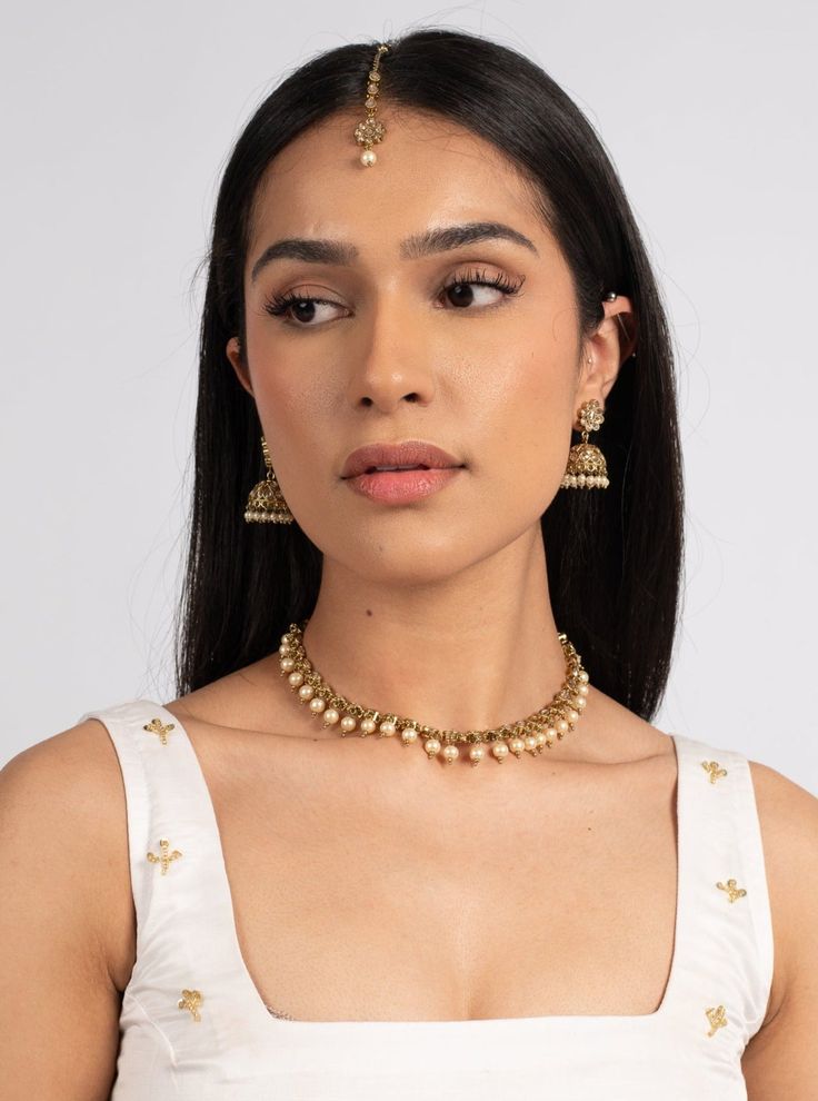 a woman wearing a gold choker and matching necklace with two pairs of earrings on her head