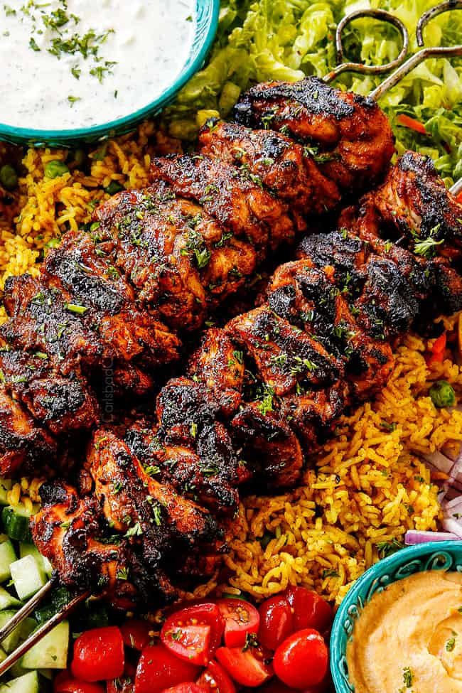 an assortment of food including chicken, rice and veggies on a platter