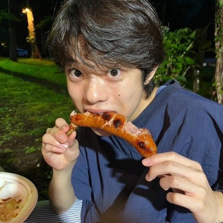 a young man eating a hot dog on top of a bun