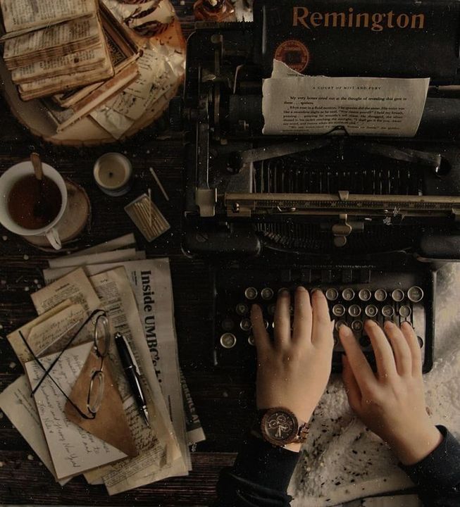 a person typing on an old typewriter surrounded by papers and other things that are scattered around