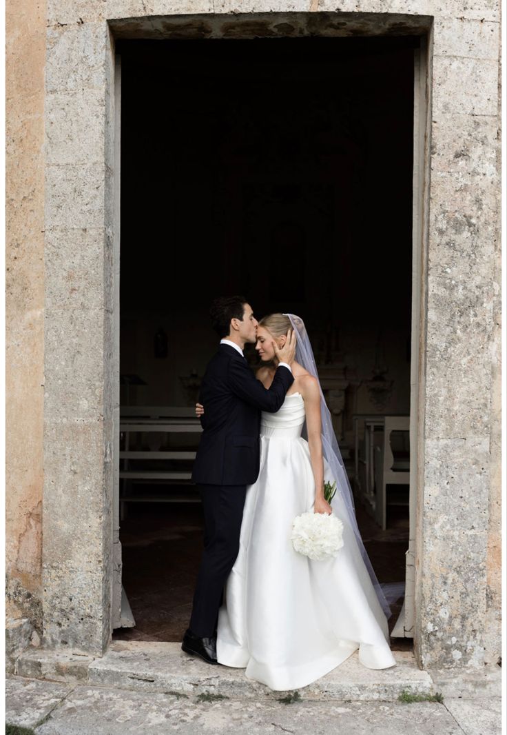 a bride and groom standing in front of a doorway