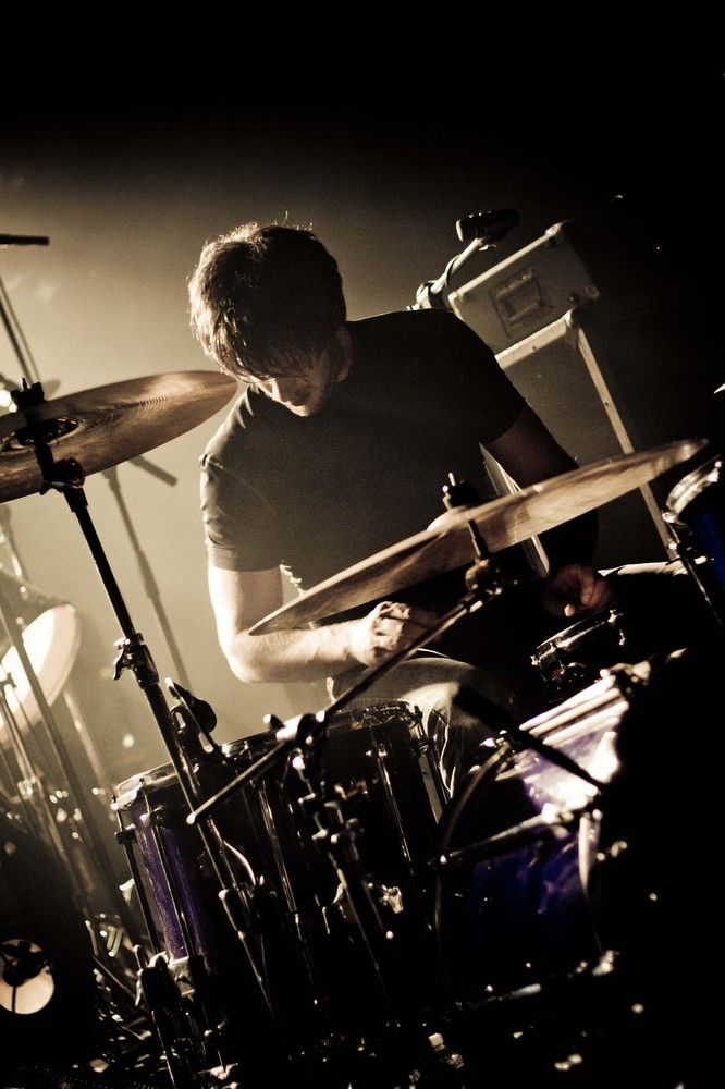 a man that is sitting in front of a drum set