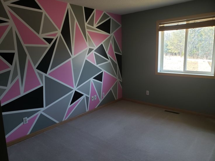 an empty room with pink, grey and black wallpaper on the walls next to a window