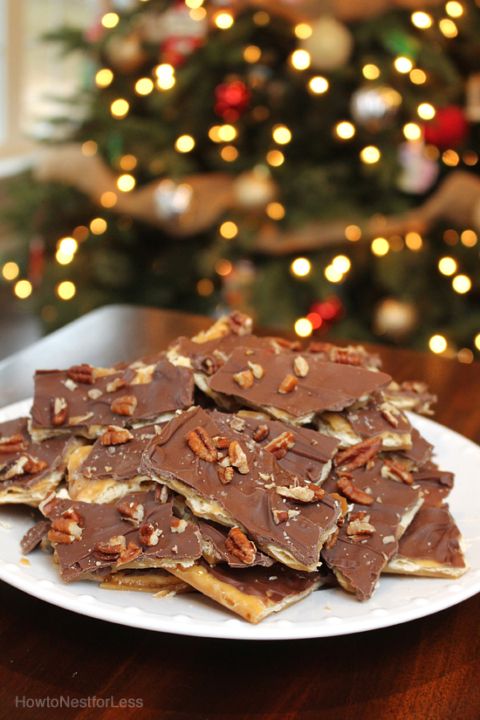 there are many pieces of chocolate and nuts on the plate with christmas lights in the background