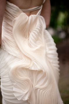 the back of a woman's white dress with pleated details