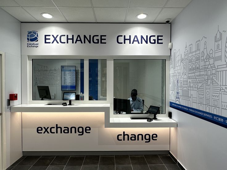 an exchange change counter with laptops and computers on it's desk in front of a wall