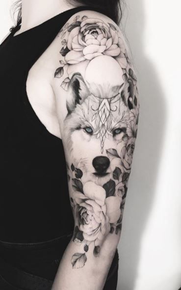 a woman's arm with roses and a wolf tattoo on her left arm,