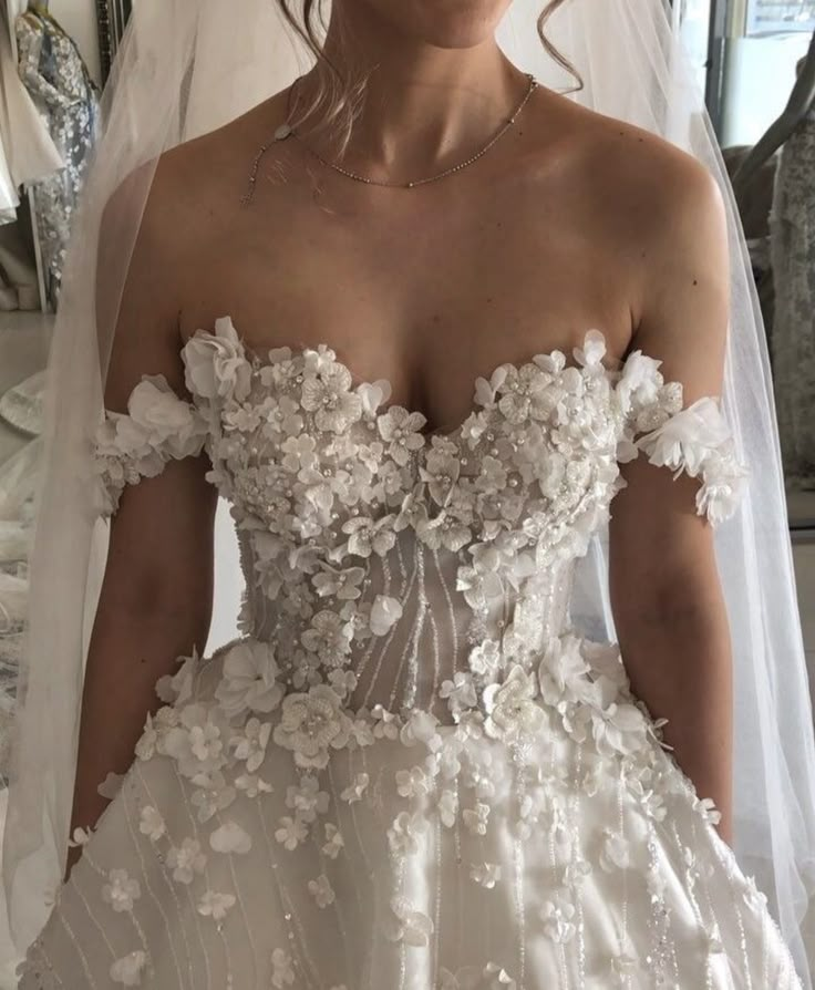 a woman wearing a wedding dress with flowers on it