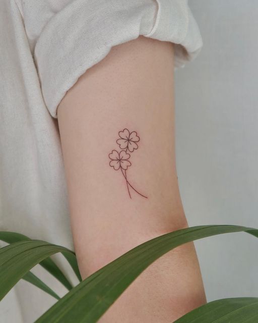 a small four leaf clover tattoo on the left inner arm, with one flower in it's center