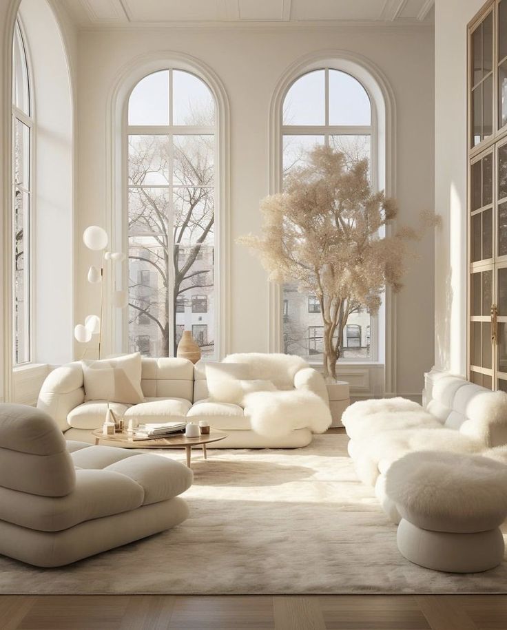 an elegant living room with white furniture and large windows