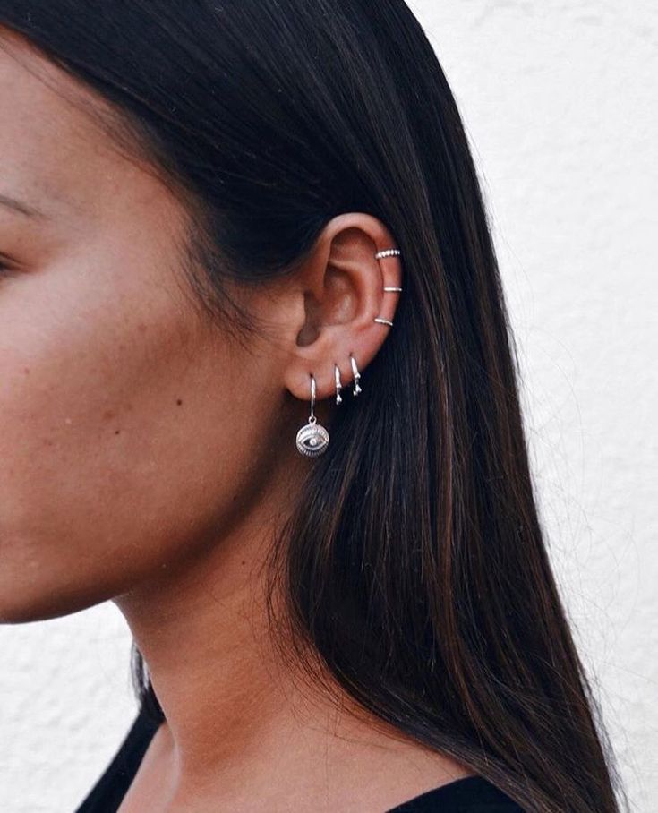 a woman wearing two earring sets on her ears