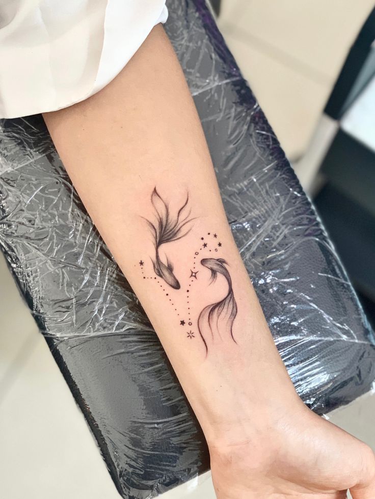 a woman's arm with a black and white koi fish tattoo on it