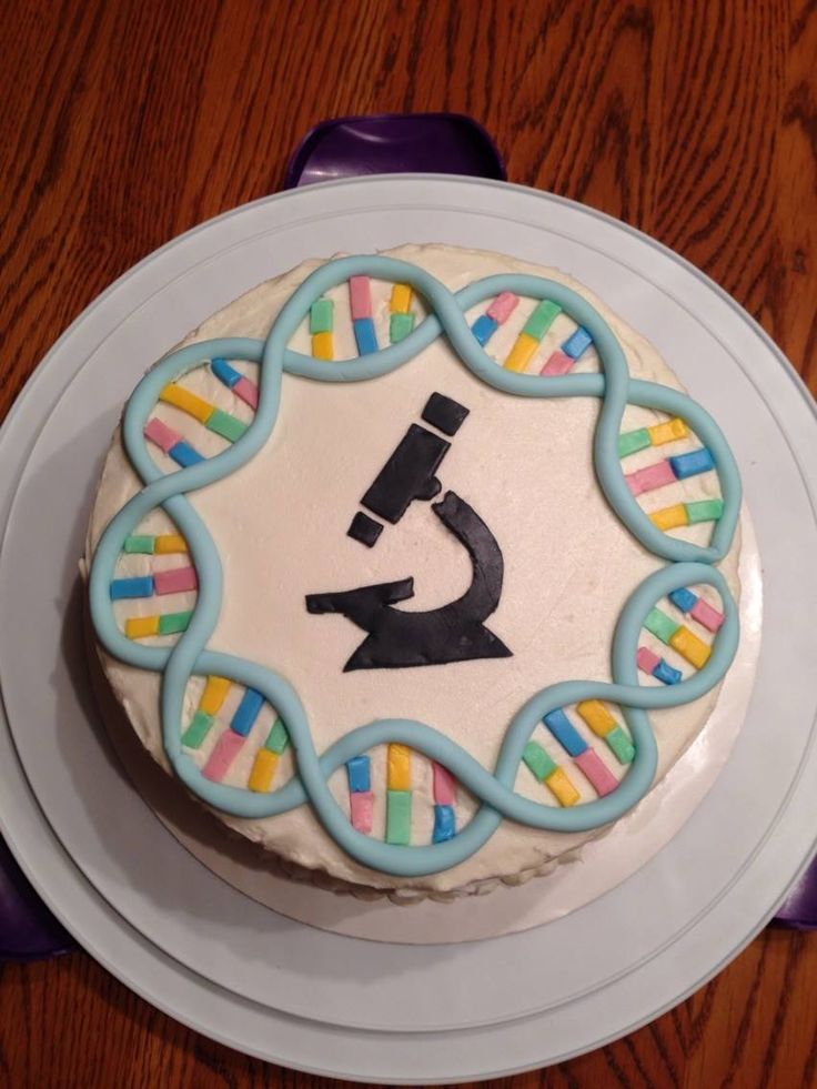 a cake that is on a plate with a microscope and rainbow icing around it