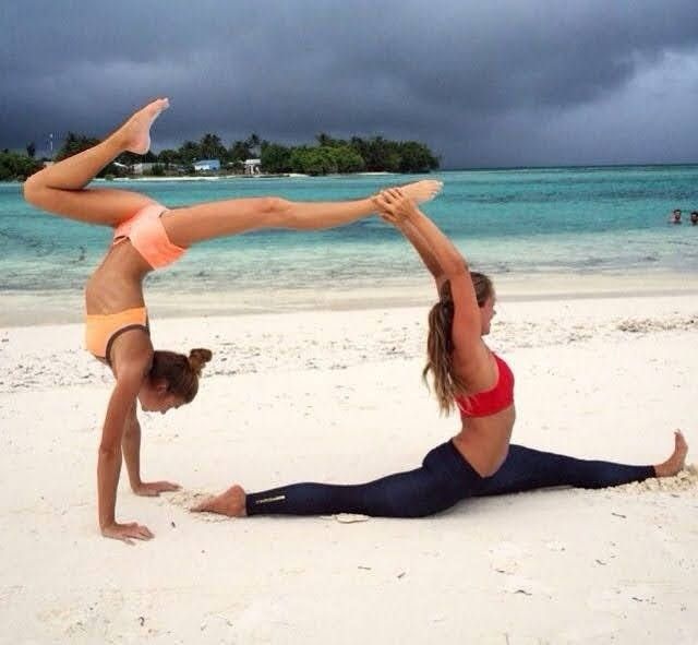 two women doing yoga on the beach with storm clouds in the sky behind them,