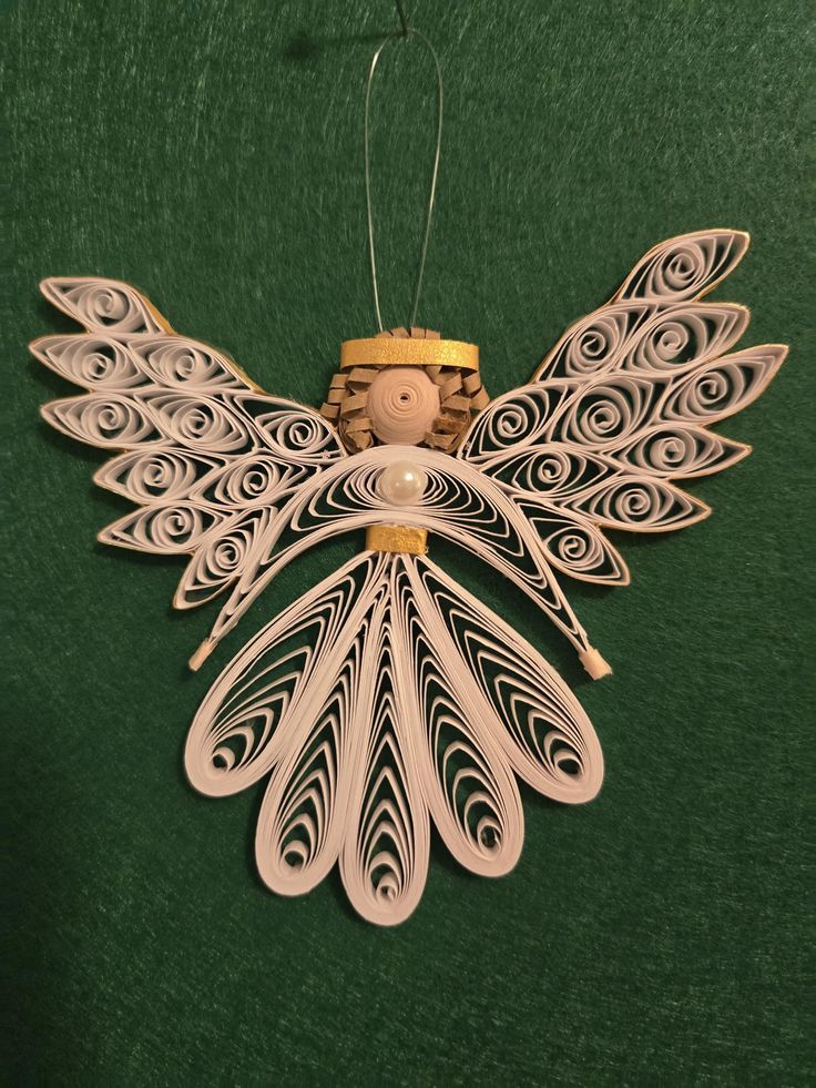 a wooden angel ornament hanging on a green wall with a string attached to it