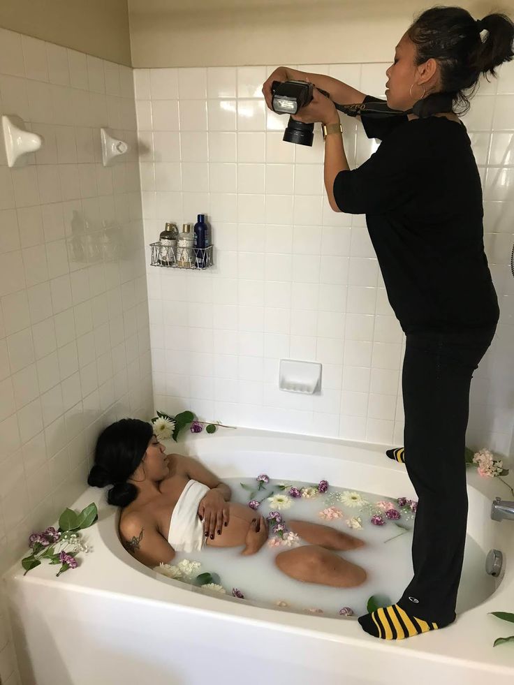 a woman is taking a photo in the bathtub