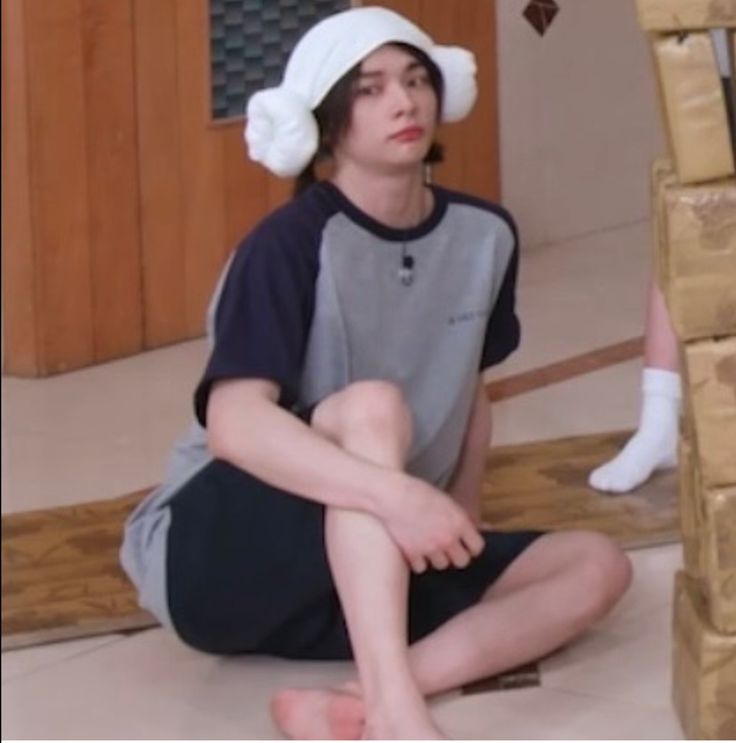 a boy sitting on the floor wearing a white hat