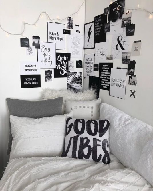 a white bed topped with lots of pillows next to a wall covered in black and white pictures