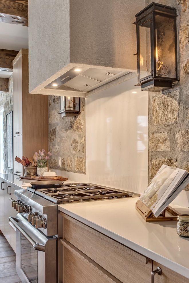 a stove top oven sitting inside of a kitchen next to a wall covered in stone