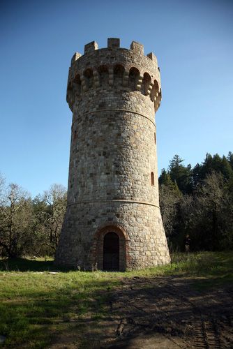 an old stone tower sitting on top of a lush green field with trees in the background