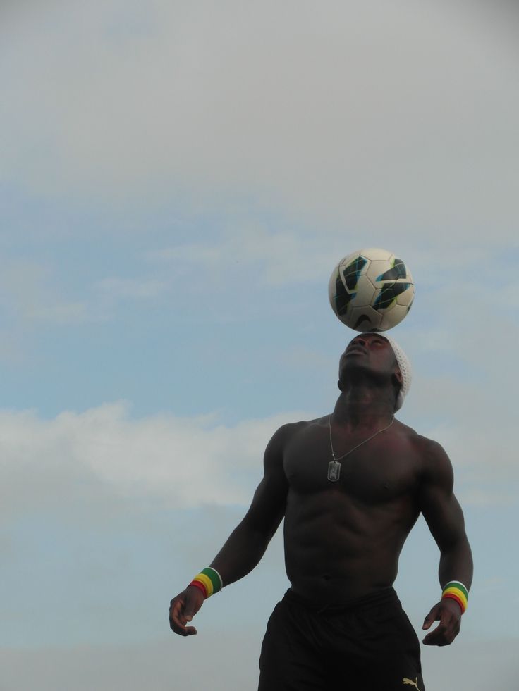 a shirtless man balancing a soccer ball on his head