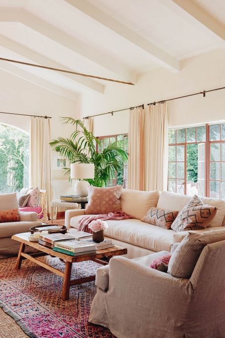 a living room with couches, chairs and rugs in front of large windows