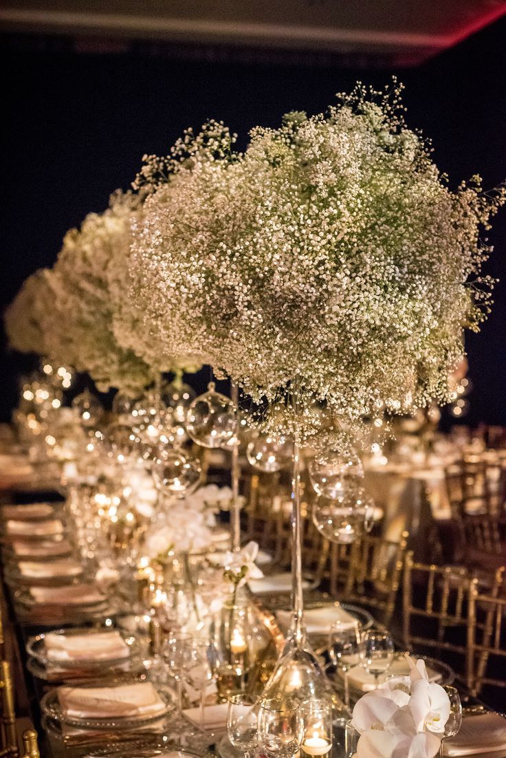 a long table with white flowers and silverware on it is set for an event