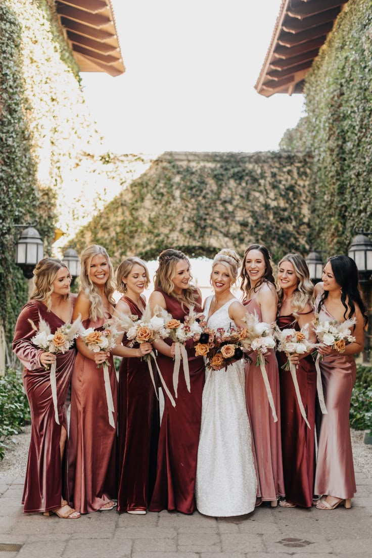 a group of women standing next to each other wearing dresses and holding bouquets in their hands