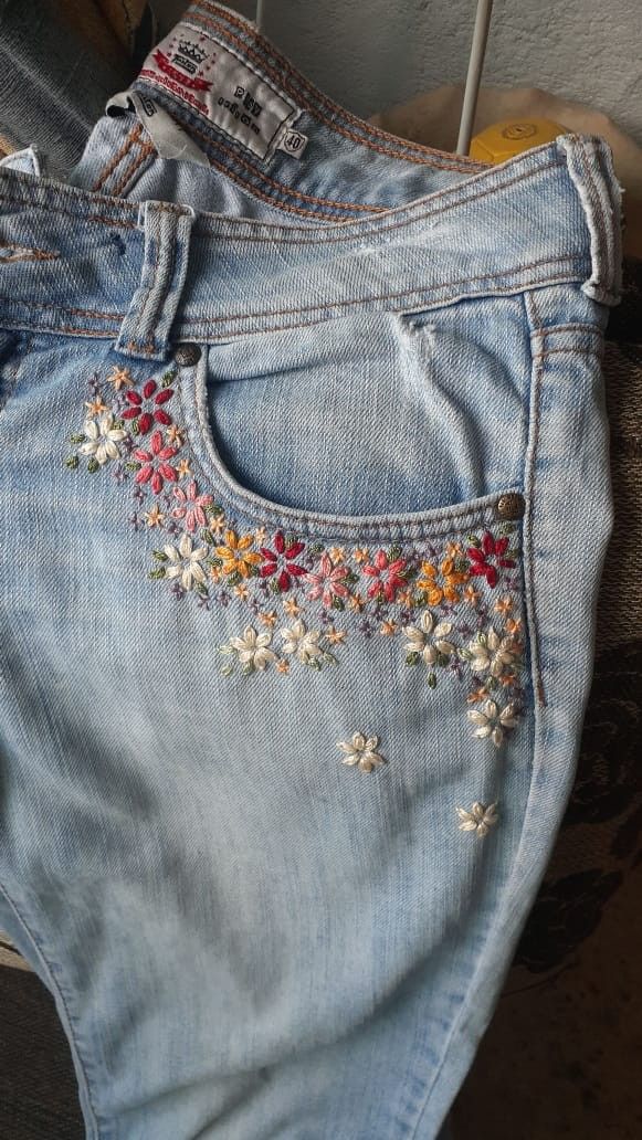 an old pair of jeans with embroidered flowers on them