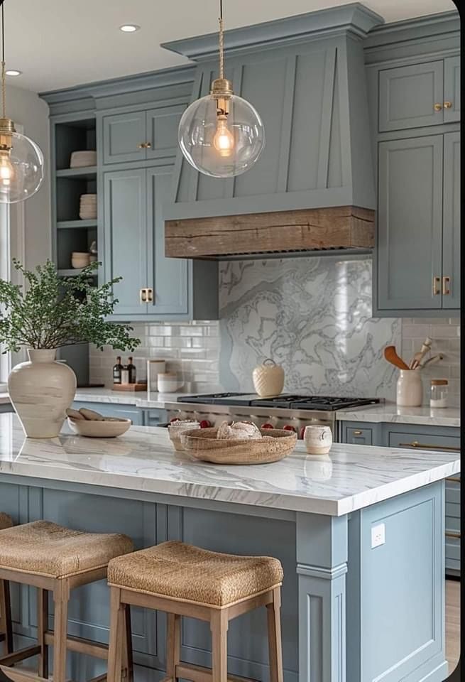 a kitchen with blue cabinets and white marble counter tops, two pendant lights over the island