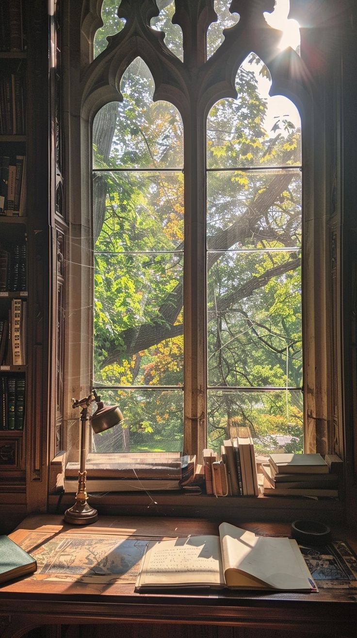 an open book sitting on top of a wooden desk in front of a large window