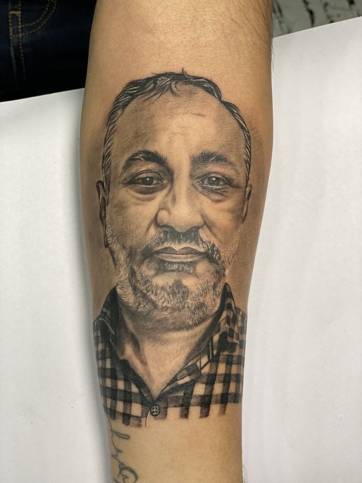 a man's leg with a portrait of him on it and his name tattooed