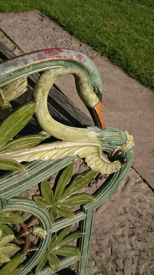 a swan statue sitting on top of a wooden bench