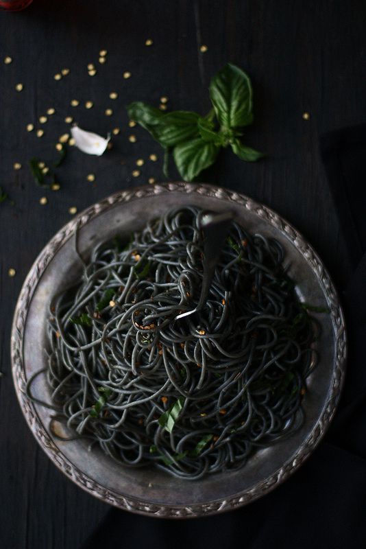 a bowl filled with pasta and basil on top of a table