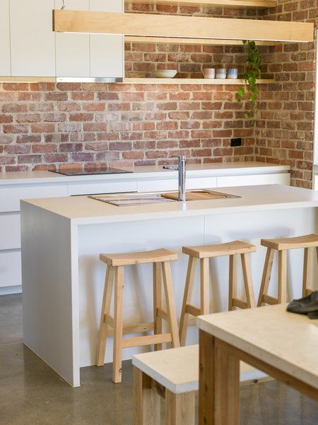 a kitchen with two stools next to an island and brick wall behind the counter