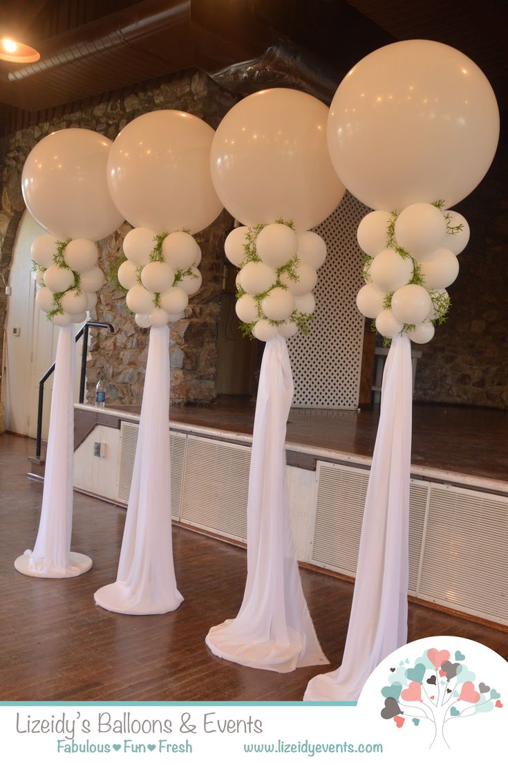 balloons and flowers are arranged in tall white vases