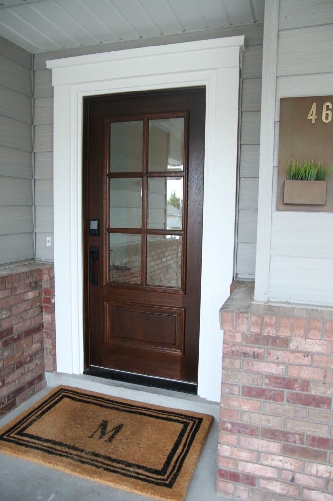 a front door with a welcome mat and brick pillars on the side of a house