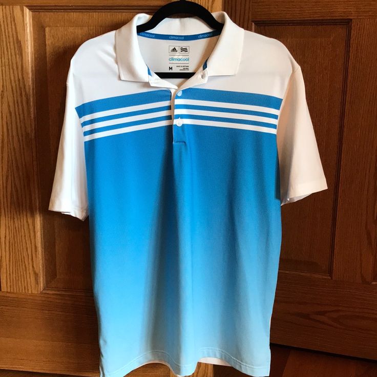 a blue and white polo shirt hanging on a wooden door with a black hanger