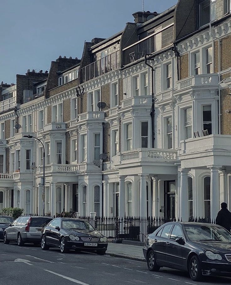 several cars parked on the street in front of row houses with white trim and balconies