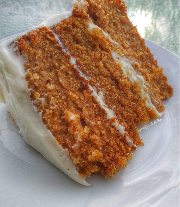 a piece of carrot cake on a plate with white frosting and icing, ready to be eaten