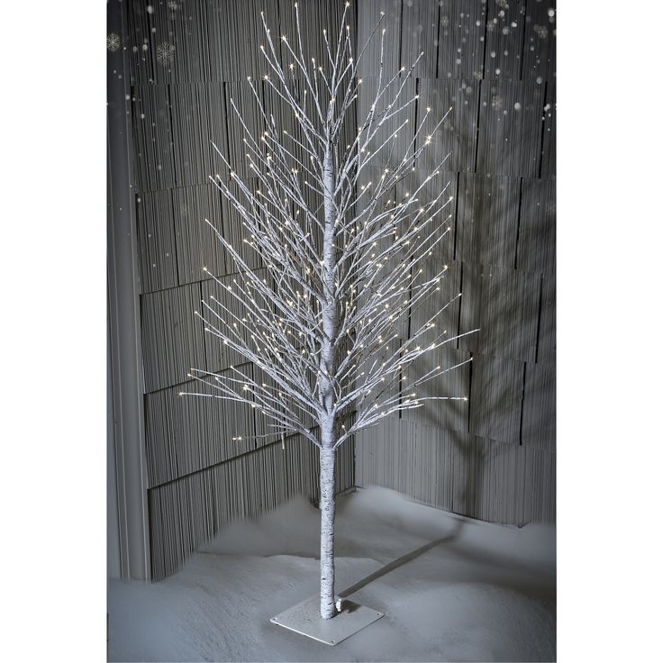 a white lighted tree stands in the snow