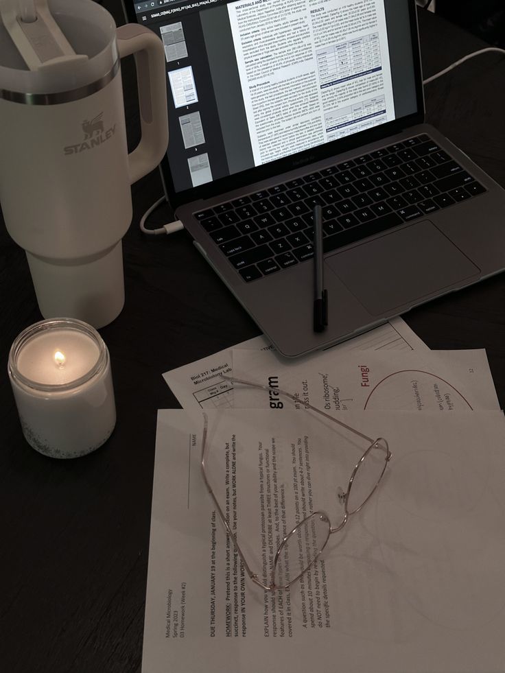 an open laptop computer sitting on top of a desk next to a cup and pen