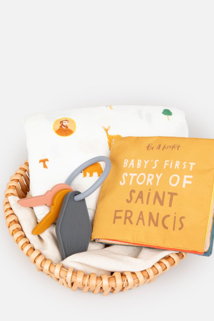 a basket filled with baby's first story of saint frances books and scissors next to a book