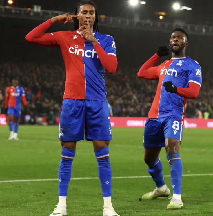 two soccer players stand on the field during a game, one is holding his hand up to his mouth