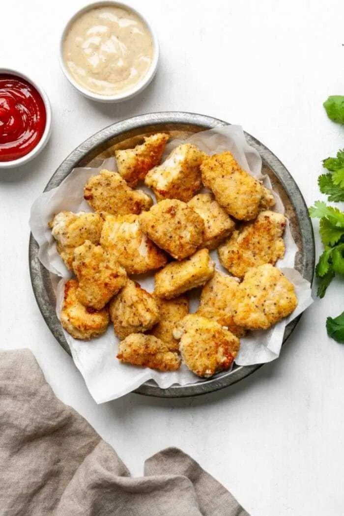 chicken nuggies on a plate with ketchup and lettuce next to it