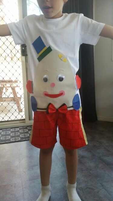 a young boy is standing in front of a door wearing shorts and a t - shirt with a cartoon character on it