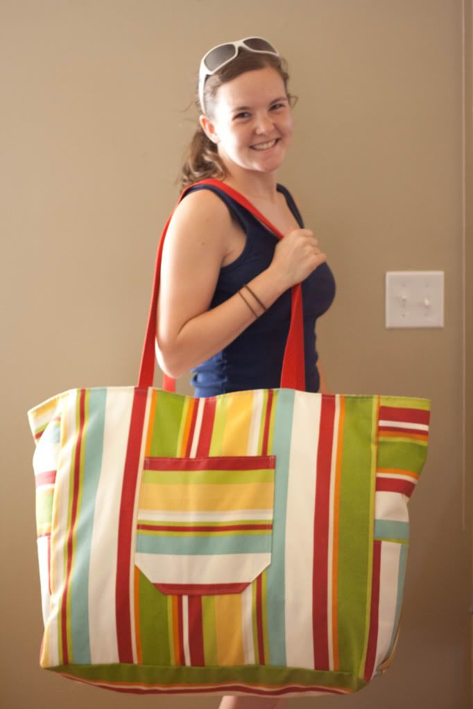 a woman holding a multicolored striped tote bag