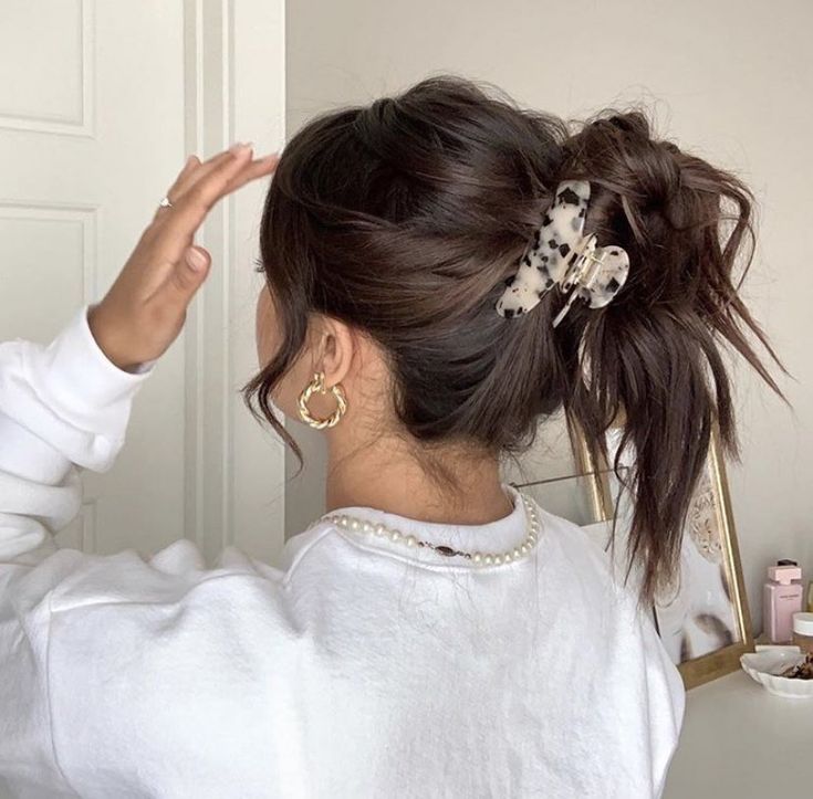 a woman with her hair in a pony tail styled up into a low ponytail and wearing a pair of gold hoop earrings