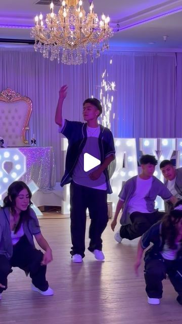 a group of young people dancing in a room with chandelier and lights on the walls